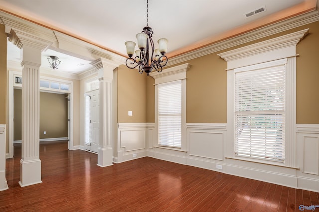 unfurnished room with a healthy amount of sunlight, decorative columns, and dark hardwood / wood-style floors