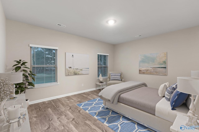 bedroom with visible vents, baseboards, and wood finished floors