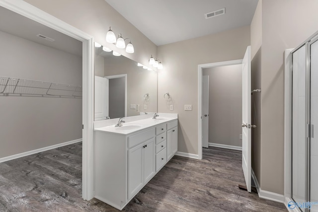 bathroom featuring a sink, visible vents, baseboards, and wood finished floors