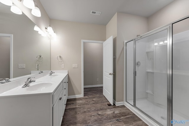 bathroom featuring visible vents, a shower stall, wood finished floors, and a sink