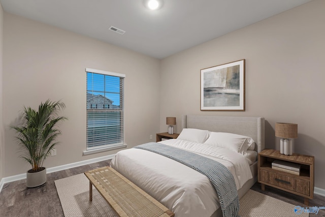 bedroom with visible vents, baseboards, and wood finished floors