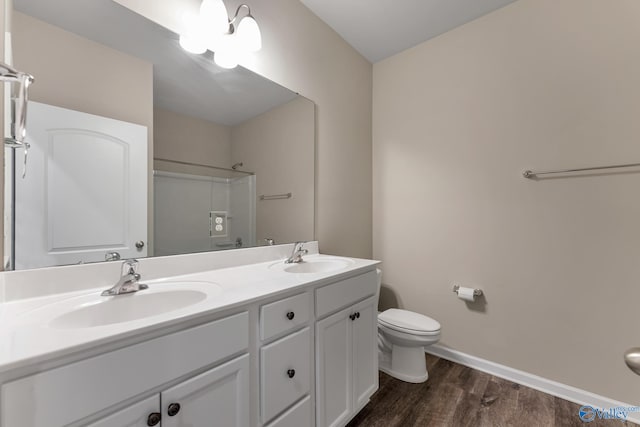 full bath with double vanity, wood finished floors, toilet, and a sink