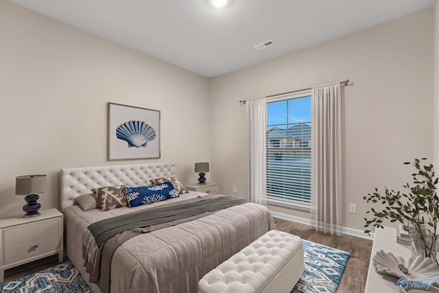 bedroom featuring visible vents, baseboards, and wood finished floors