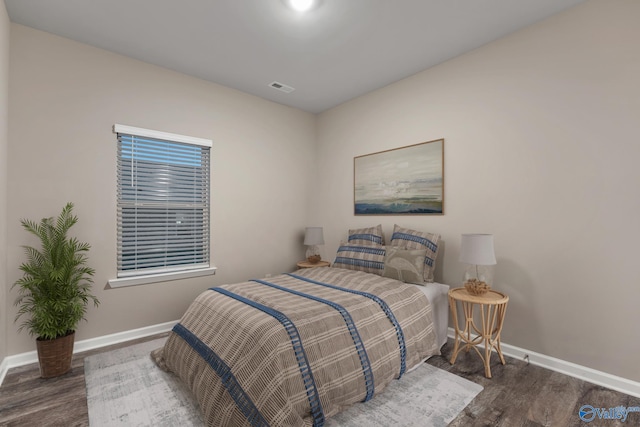 bedroom with wood finished floors, visible vents, and baseboards