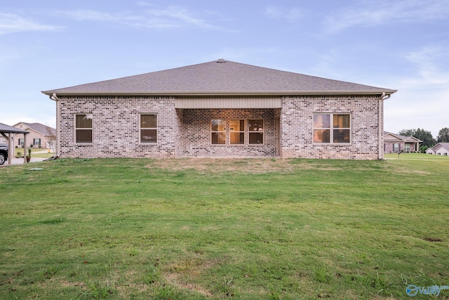 back of property featuring brick siding, a shingled roof, and a yard