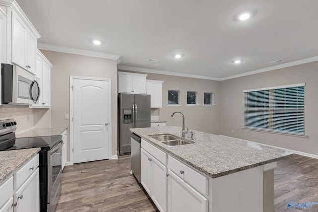 kitchen featuring ornamental molding, a sink, wood finished floors, stainless steel appliances, and decorative backsplash