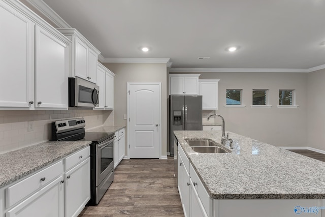 kitchen featuring a kitchen island with sink, a sink, dark wood-style floors, appliances with stainless steel finishes, and decorative backsplash