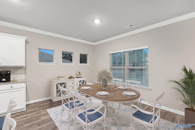 dining room with visible vents, crown molding, light wood-type flooring, and baseboards