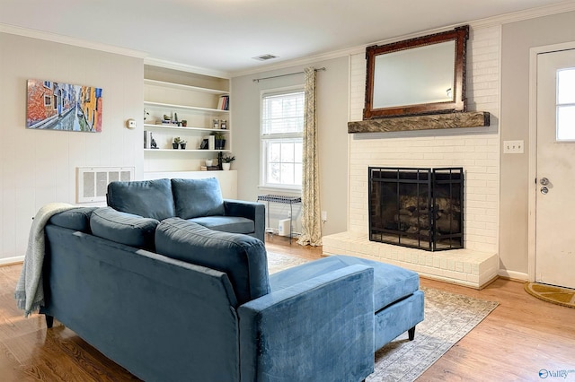 living room featuring ornamental molding, a brick fireplace, radiator, and hardwood / wood-style floors