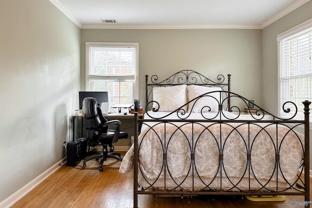 bedroom featuring multiple windows, crown molding, and light wood-type flooring