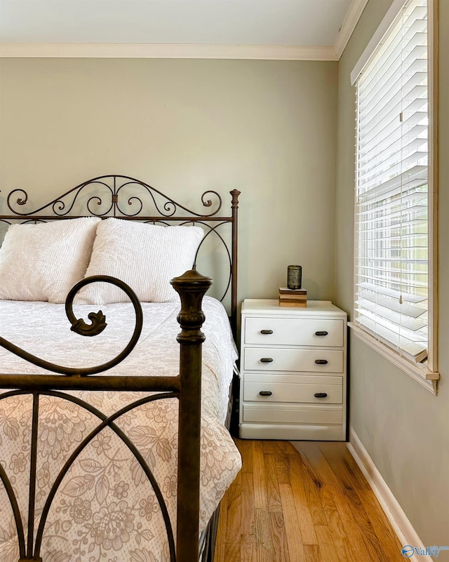 bedroom featuring crown molding and light hardwood / wood-style flooring