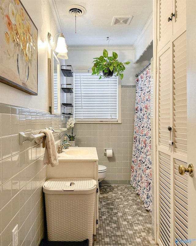 bathroom with tile patterned floors, ornamental molding, toilet, and tile walls