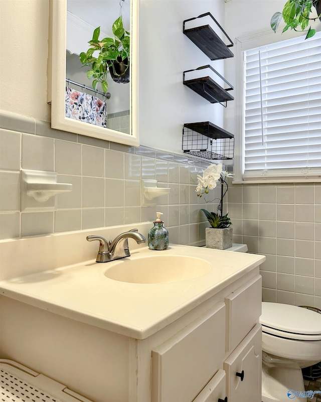 bathroom with vanity, toilet, and tile walls