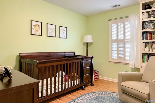 bedroom with a nursery area and light wood-type flooring