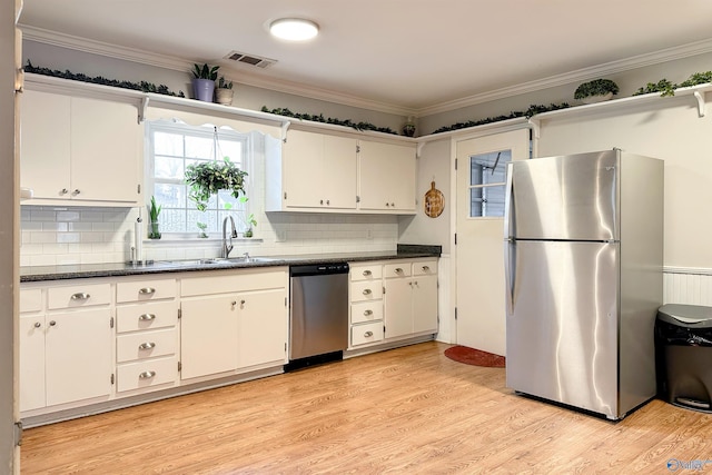 kitchen with white cabinets, appliances with stainless steel finishes, sink, and dark stone counters