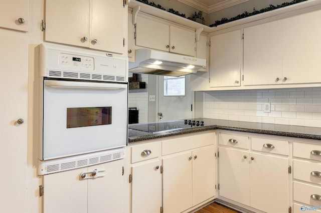 kitchen featuring tasteful backsplash, dark stone countertops, crown molding, white oven, and black electric cooktop