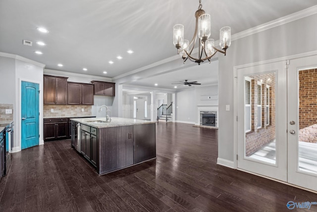 kitchen featuring dark brown cabinets, a kitchen island with sink, sink, decorative light fixtures, and dark hardwood / wood-style floors