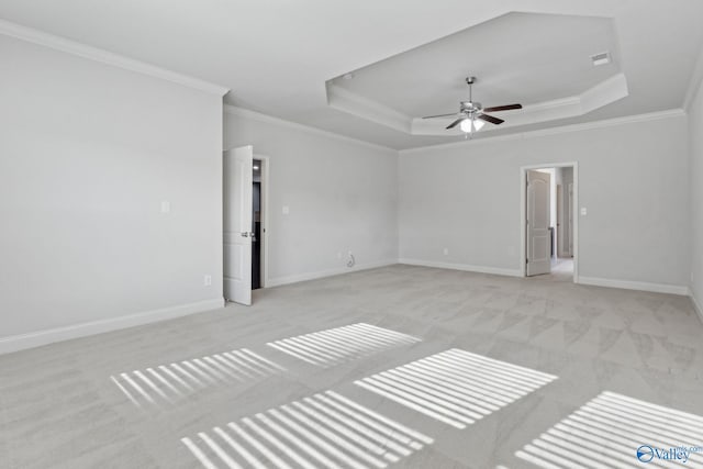 unfurnished room with light colored carpet, ceiling fan, crown molding, and a tray ceiling