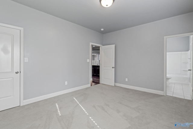 unfurnished bedroom featuring ensuite bathroom and light colored carpet