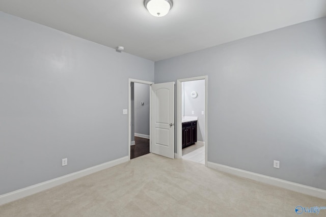 unfurnished bedroom featuring light carpet and connected bathroom