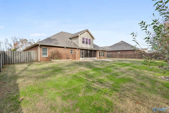 back of property with a sunroom, a patio, and a lawn