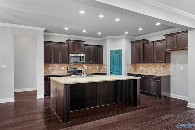 kitchen featuring dark brown cabinetry, stainless steel appliances, dark wood-type flooring, and an island with sink