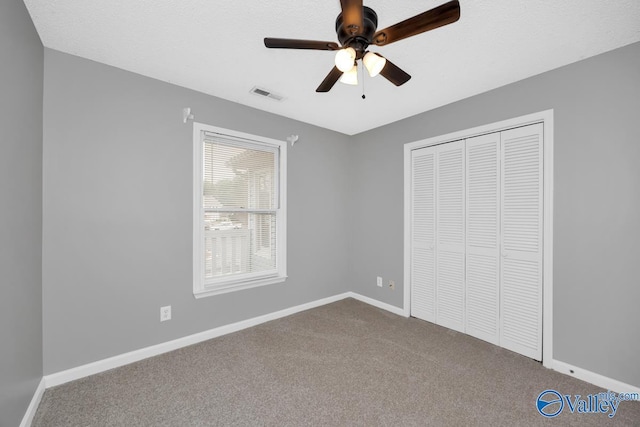 unfurnished bedroom with carpet, ceiling fan, a textured ceiling, and a closet