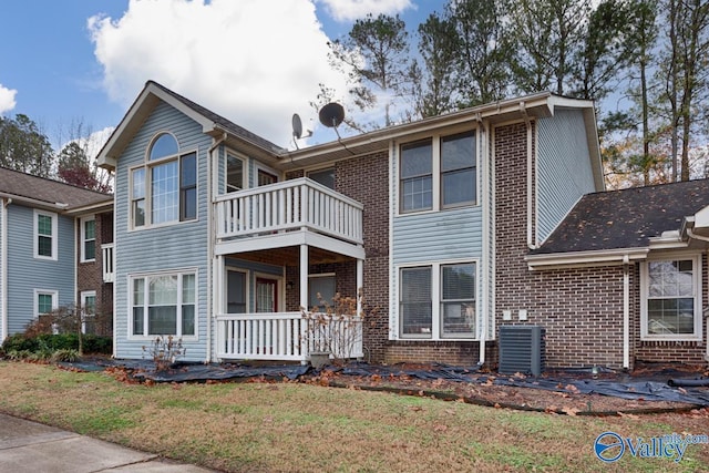 view of front of house featuring central AC, a balcony, and a front yard