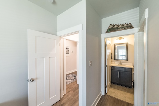 hall with baseboards, a sink, and dark wood-type flooring