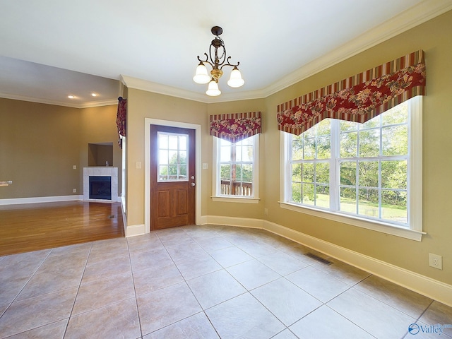 tiled foyer entrance featuring a notable chandelier, a fireplace, and ornamental molding