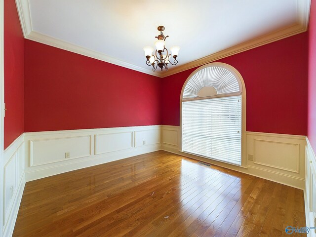 unfurnished room with a notable chandelier, wood-type flooring, and ornamental molding