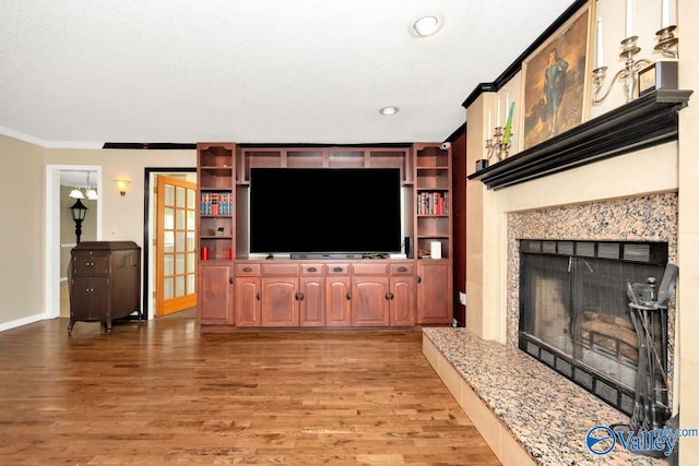 living room with a premium fireplace, light wood-type flooring, crown molding, and a textured ceiling