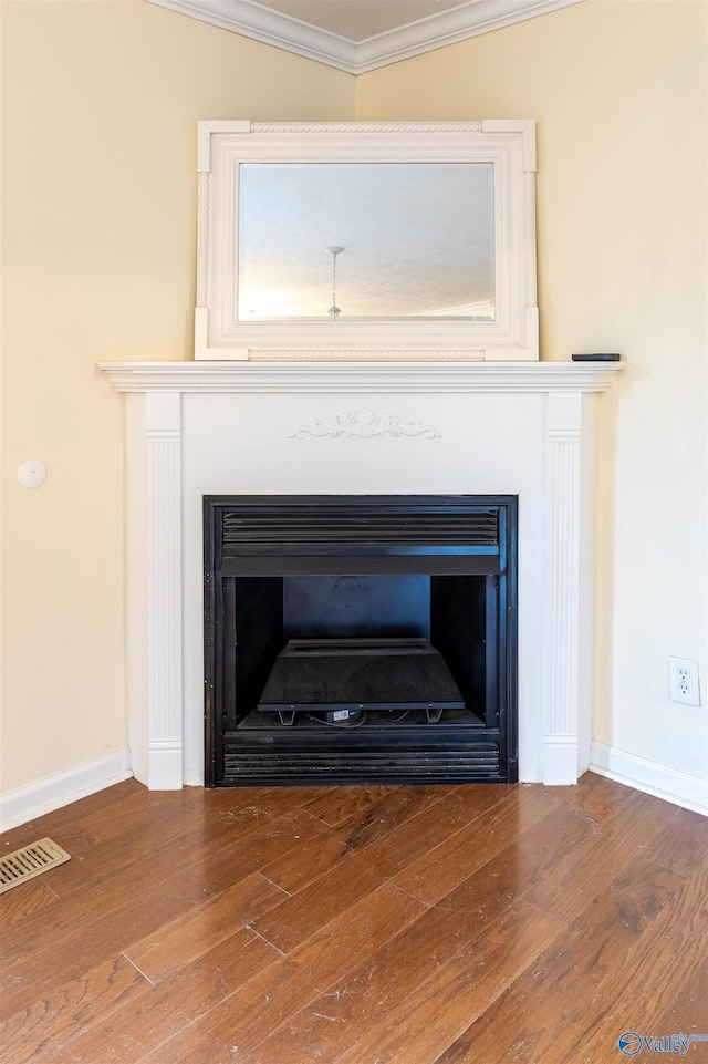 interior details featuring visible vents, a fireplace, ornamental molding, and wood finished floors