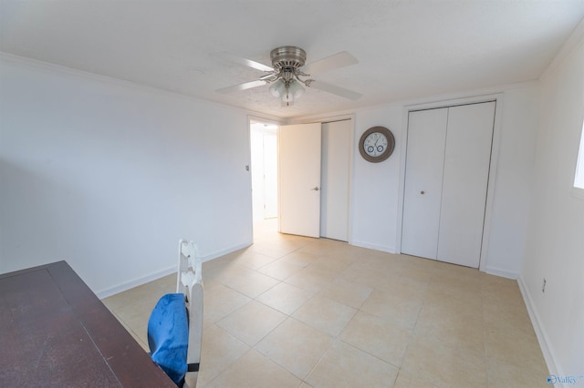 unfurnished bedroom featuring a ceiling fan, baseboards, multiple closets, and light tile patterned flooring