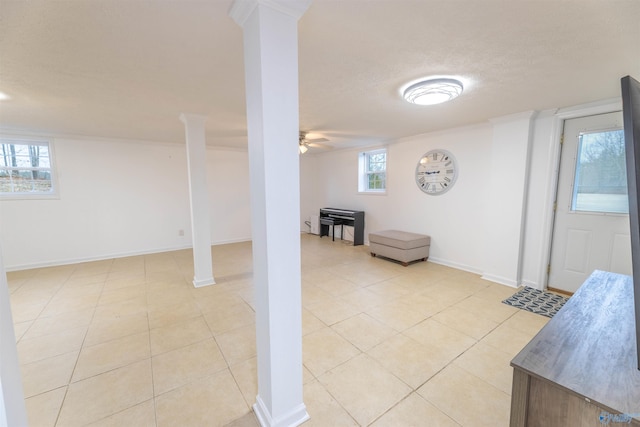 below grade area with a textured ceiling, light tile patterned flooring, a ceiling fan, and baseboards