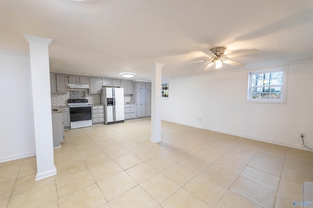 unfurnished living room featuring a ceiling fan, decorative columns, baseboards, and light tile patterned floors