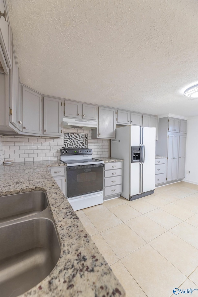 kitchen with tasteful backsplash, gray cabinets, a sink, white appliances, and under cabinet range hood