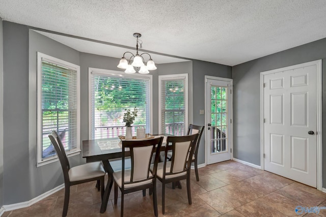 dining area with plenty of natural light, a chandelier, tile patterned flooring, and a textured ceiling