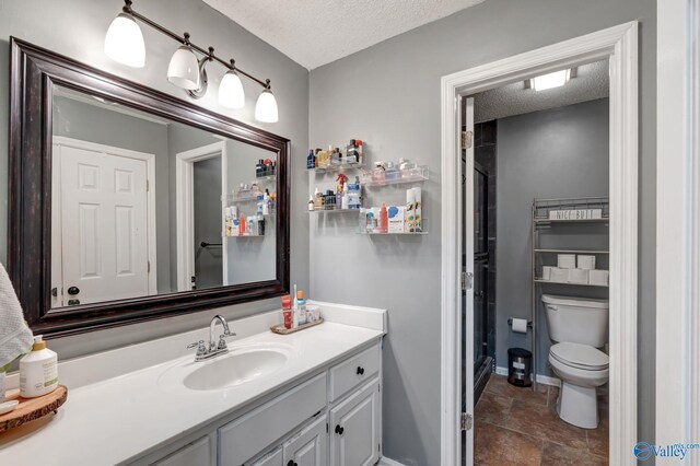 bathroom with vanity, toilet, a textured ceiling, and tile patterned flooring