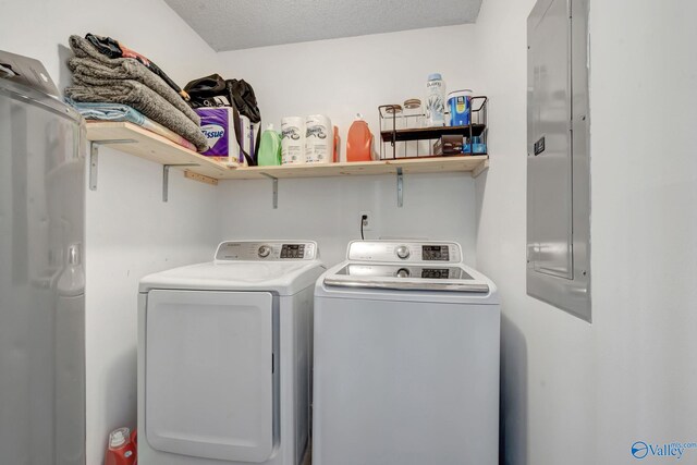 washroom featuring washing machine and dryer, a textured ceiling, and electric panel