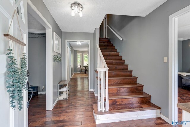 stairs featuring dark hardwood / wood-style flooring, a textured ceiling, and crown molding