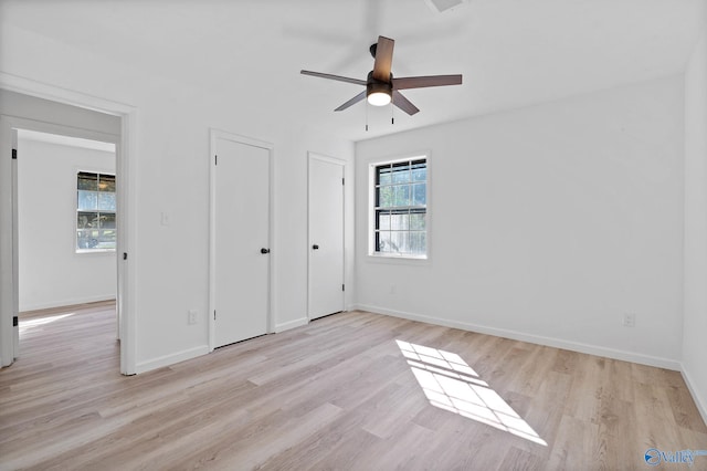 unfurnished bedroom with ceiling fan, two closets, and light hardwood / wood-style floors