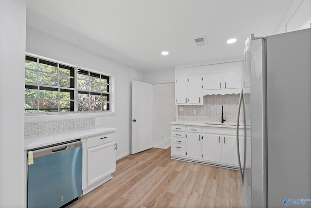 kitchen with light wood-type flooring, refrigerator, sink, white cabinets, and stainless steel dishwasher