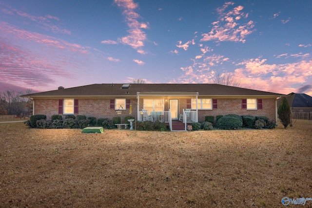 ranch-style home featuring brick siding and a porch