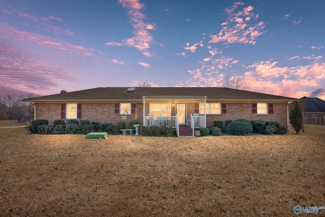 single story home featuring covered porch and a lawn