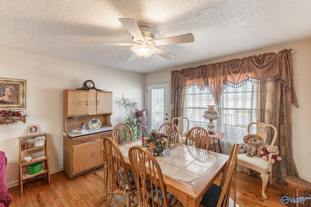 dining room featuring ceiling fan, a textured ceiling, and light hardwood / wood-style flooring