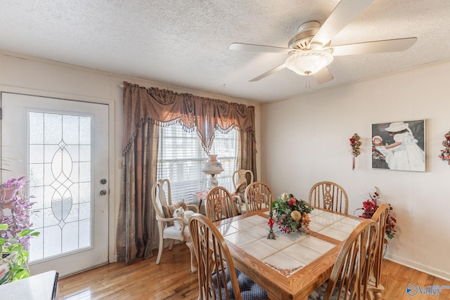 dining space with a textured ceiling, ceiling fan, and light wood finished floors