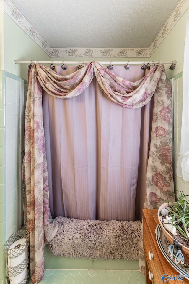 bathroom with a shower with curtain, tile patterned flooring, and a textured ceiling