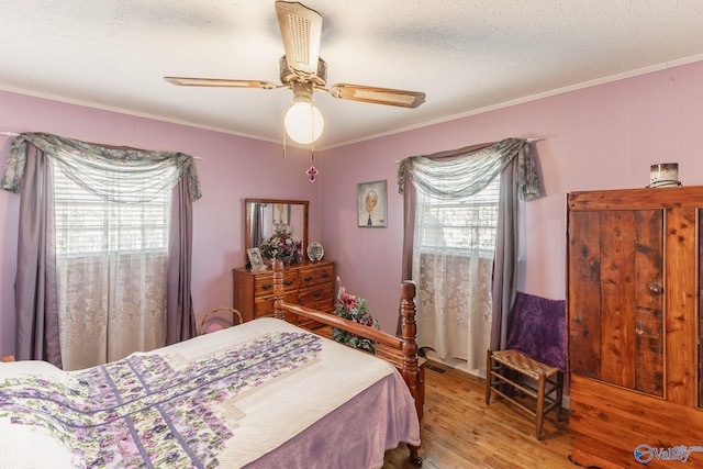 bedroom with crown molding, ceiling fan, hardwood / wood-style floors, and multiple windows