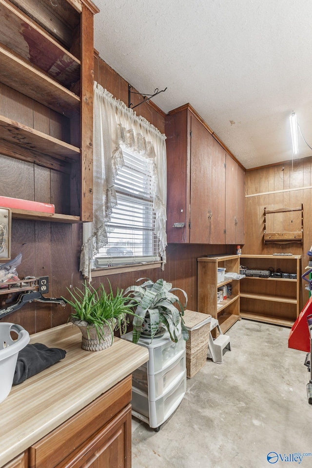 interior space featuring a textured ceiling and wood walls